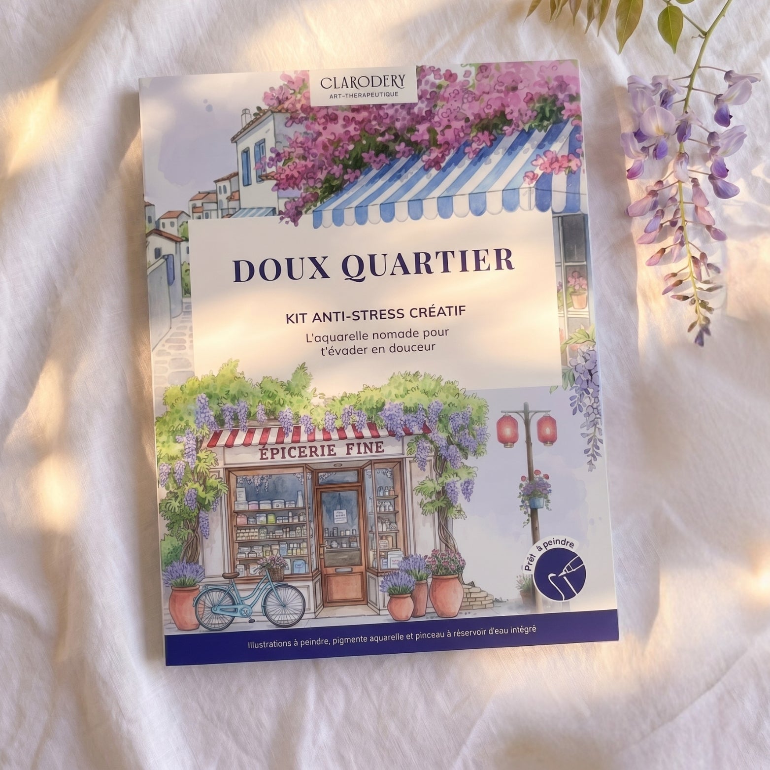 Kit anti-stress créatif Doux Quartier de Clarodery, illustré d'une épicerie fine, d'une glycine et d'un vélo bleu.